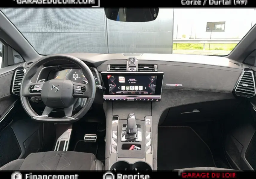 Vue intérieure avant du tableau de bord noir et volant cuir du DS7 Crossback blanc, avec écran tactile central allumé.