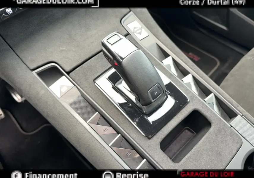 Gros plan sur la console centrale noire avec levier de vitesse automatique et commandes des vitres du DS7 Crossback blanc.