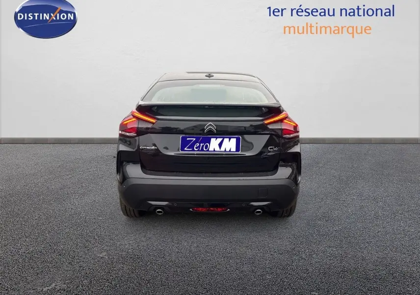 Vue arrière d'une Citroën C4 noire métal 2024 avec feux LED allumés et double sortie d'échappement visible.