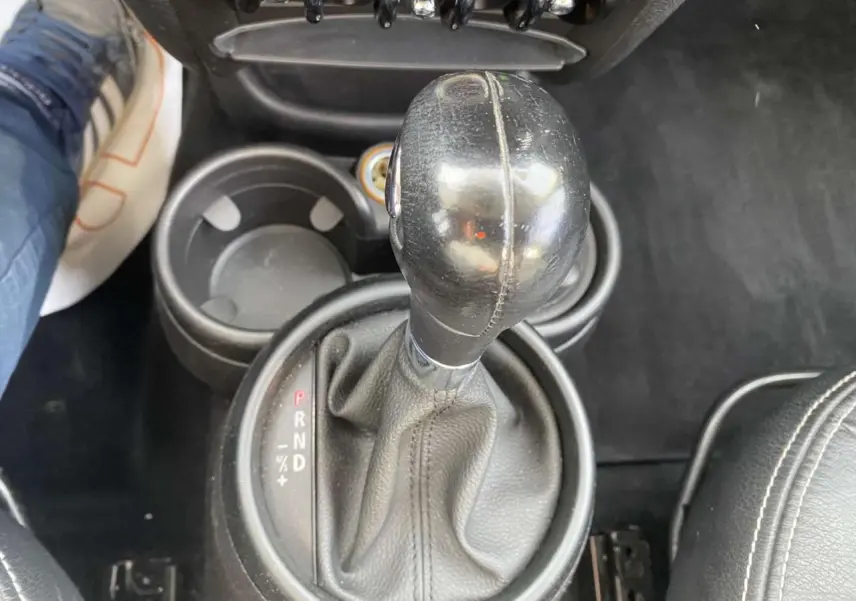 Le levier de vitesse automatique en cuir noir de la MINI Countryman 2015, avec porte-gobelets et siège en cuir visible.