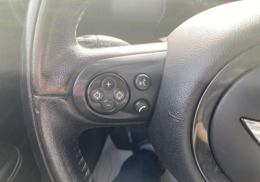 Gros plan sur les commandes vocales et téléphone intégrées au volant en cuir noir du MINI Countryman gris clair.