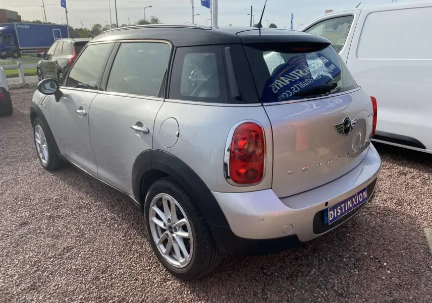 Vue 3/4 arrière droite d'une MINI Countryman gris clair avec toit noir et feux arrière rouges.