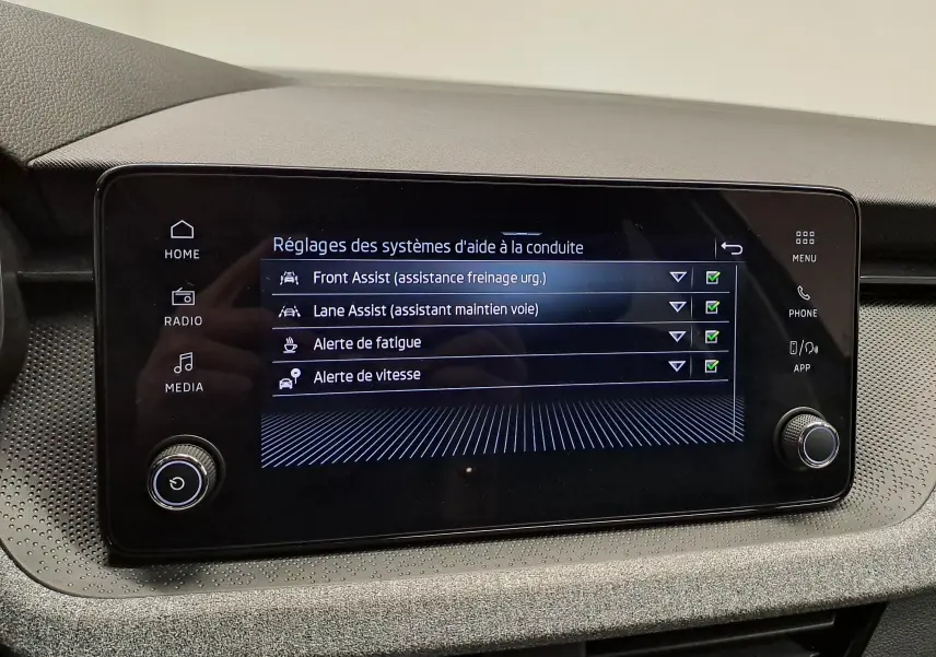 Écran tactile central du Skoda Kamiq 2025 affichant les réglages d'aide à la conduite, intérieur gris sobre.