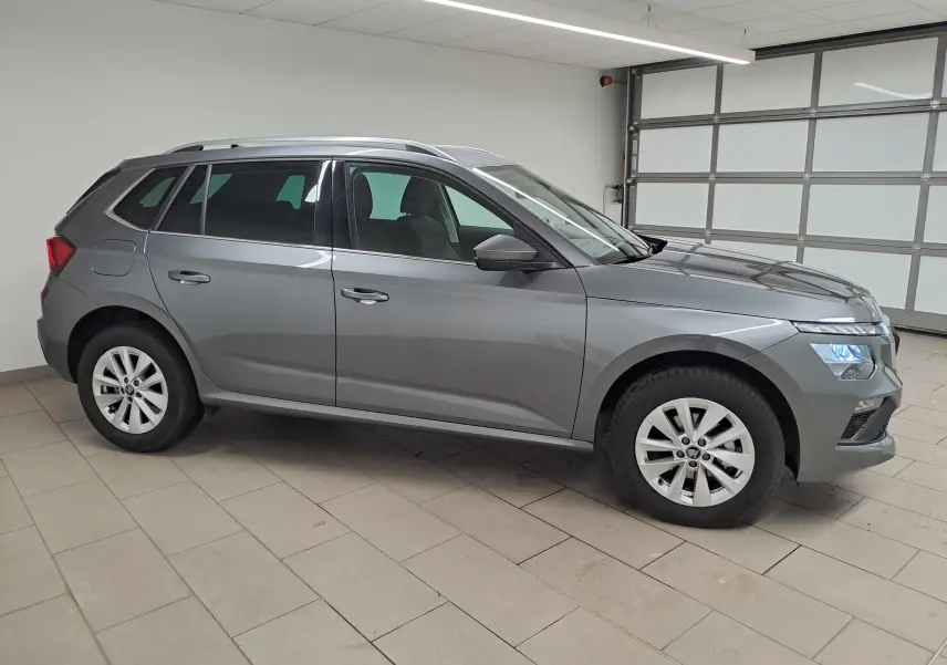 Vue de profil côté gauche d’un Skoda Kamiq gris graphite 2025 avec jantes alliage et caméra de recul visible.