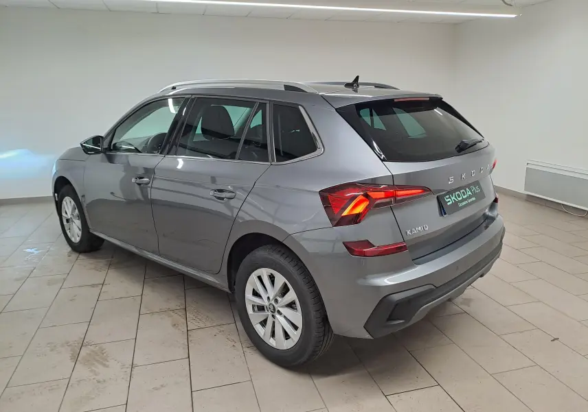 Vue 3/4 arrière droite du Skoda Kamiq 2025 gris graphite avec feux allumés et caméra de recul visible.
