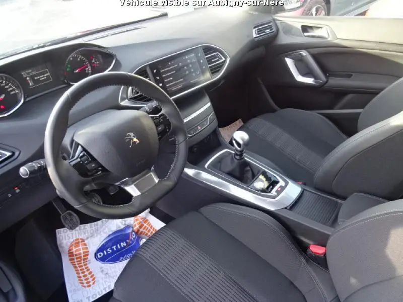 Vue intérieure avant droite du Peugeot 308 SW noir de 2018, volant compact, écran tactile et levier de boîte manuelle visibles.