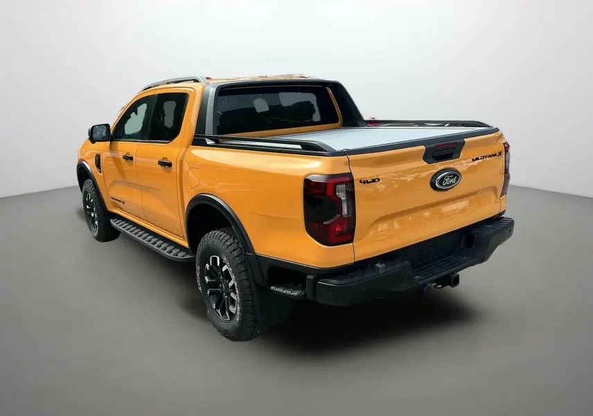 Ford Ranger 2025 Cyber orange en 3/4 arrière droit, avec benne couverte et jantes noires tout-terrain.