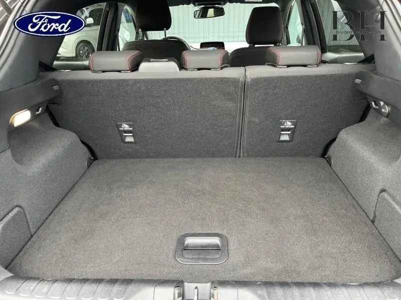 Vue du coffre arrière ouvert du Ford Puma noir, montrant la banquette arrière rabattue et l'espace de chargement spacieux.