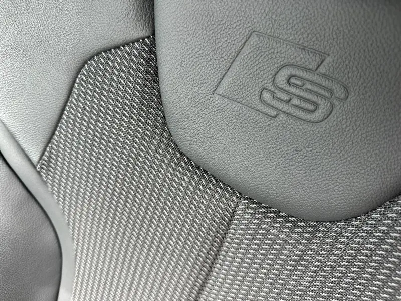 Gros plan sur le siège avant en cuir et tissu gris avec logo S embossé, intérieur de l'Audi Q2 30 TDI 2024.