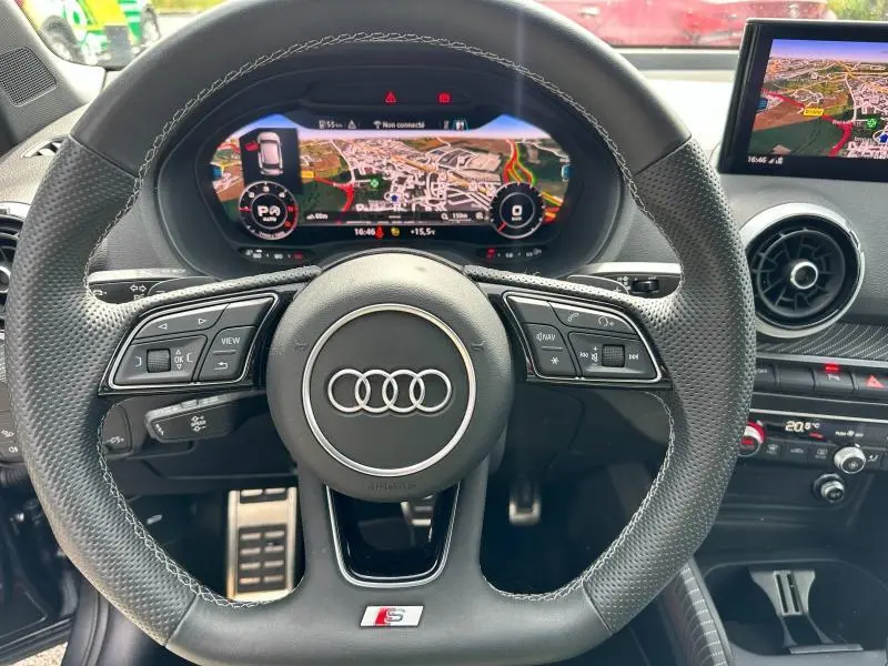 Vue rapprochée du volant sport en cuir noir de l'Audi Q2 30 TDI 2024 avec tableau de bord numérique affichant la navigation.