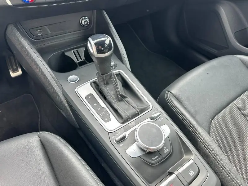 Vue rapprochée de la console centrale avec levier de vitesse et commandes multimédia d’un Audi Q2 gris Daytona nacré.