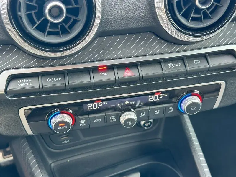 Détail de la console centrale de l'Audi Q2 30 TDI 116ch S line 2024, avec commandes climatisation et finition gris Daytona nacré.