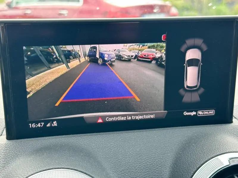 Écran de caméra de recul de l'Audi Q2 gris Daytona montrant une vue arrière avec repères de trajectoire colorés.