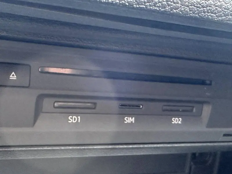 Gros plan sur le lecteur de cartes SD et SIM intégré dans l'Audi Q2 30 TDI 116ch S line gris Daytona nacré.