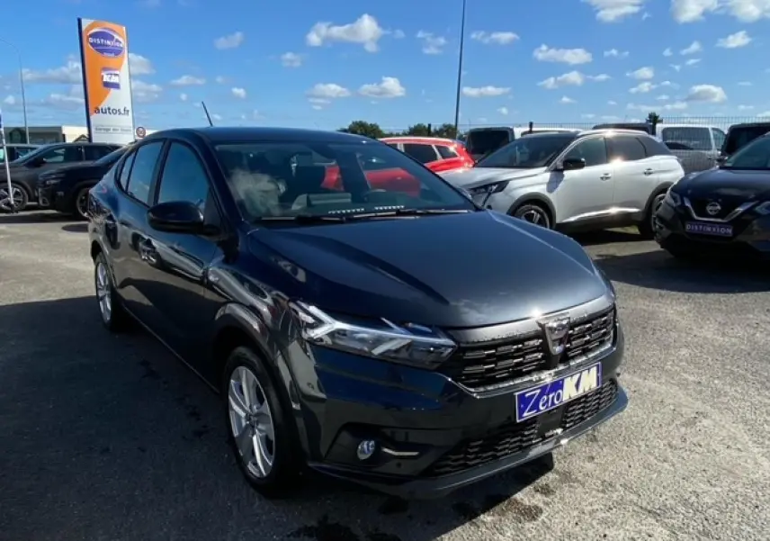 Dacia Logan gris vue 3/4 avant droit sur parking, avec calandre noire et phares LED distinctifs.