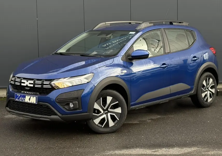 Vue 3/4 avant droite d'une Dacia Sandero Stepway 2025 Bleu Iron avec barres de toit et jantes spécifiques.