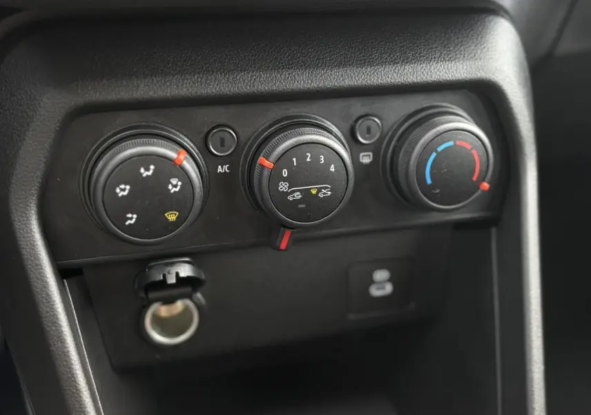 Gros plan sur les commandes de climatisation manuelle du tableau de bord du Dacia Sandero Stepway Bleu Iron 2025.