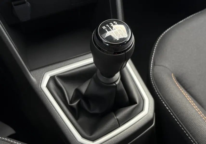 Gros plan sur le levier de vitesses manuel noir de la Dacia Sandero Stepway 2025, avec coutures apparentes sur la sellerie grise.