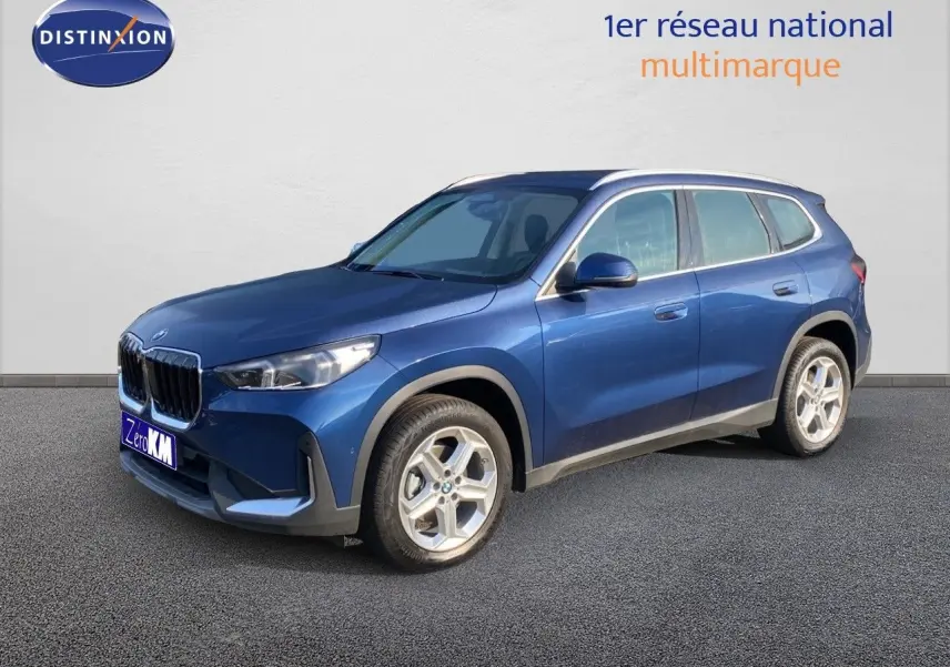 BMW X1 18I 136CH bleu Phytonic metal en 3/4 avant droit, mettant en valeur sa calandre et ses jantes argentées.
