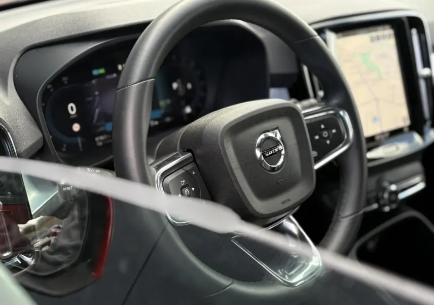 Vue rapprochée du volant noir du Volvo XC40 avec tableau de bord digital et écran tactile de navigation visible.