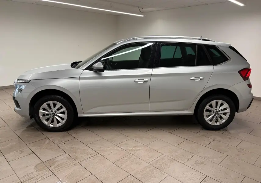 Vue latérale droite d'un Skoda Kamiq gris argent 2025 avec peinture métallisée et caméra de recul visible sur le hayon.