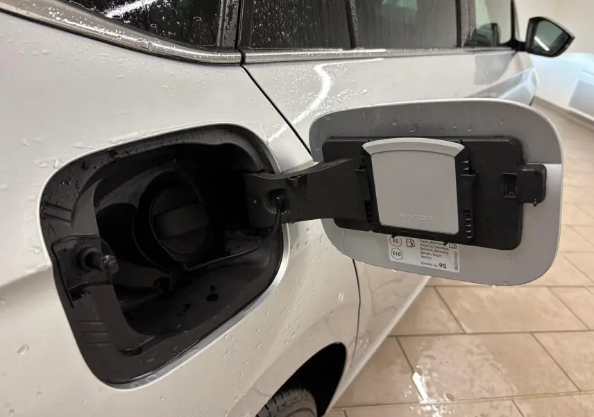 Vue rapprochée de la trappe à carburant ouverte côté gauche d’un Skoda Kamiq gris argent 2025.