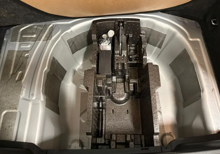 Coffre ouvert du Skoda Kamiq 2025 gris argent, vue plongeante sur le rangement pour roue de secours et outils.