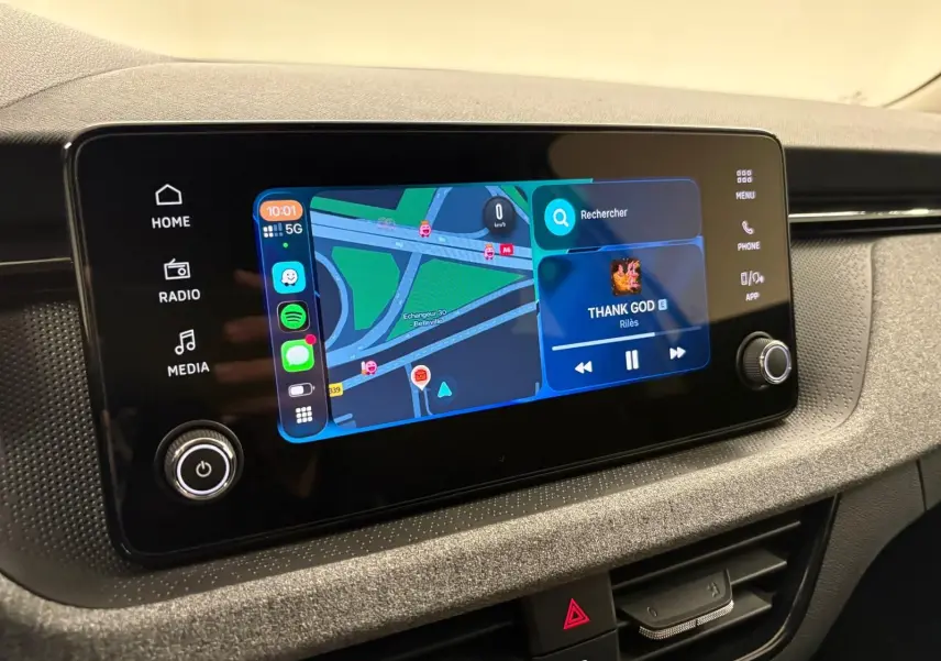 Écran tactile central du Skoda Kamiq 2025 affichant navigation et musique, avec commandes tactiles et bouton rotatif.