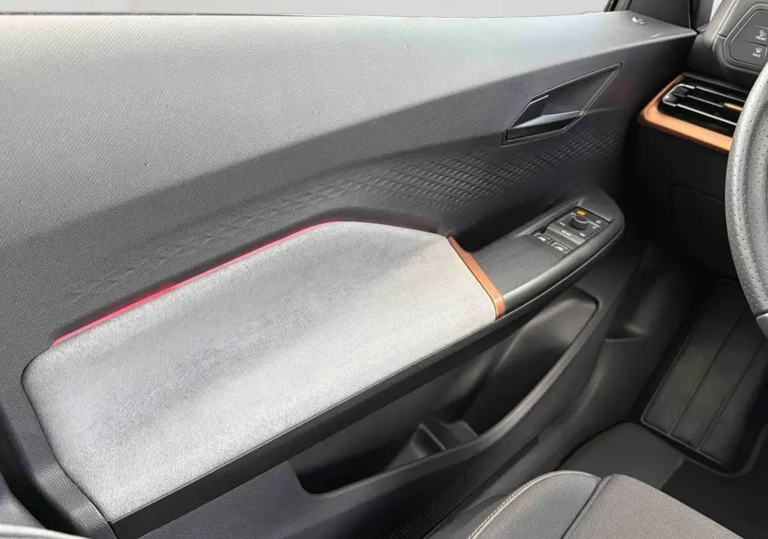 Vue intérieure côté gauche de la porte avant du CUPRA Born 2024 avec garniture grise et détails cuivrés.