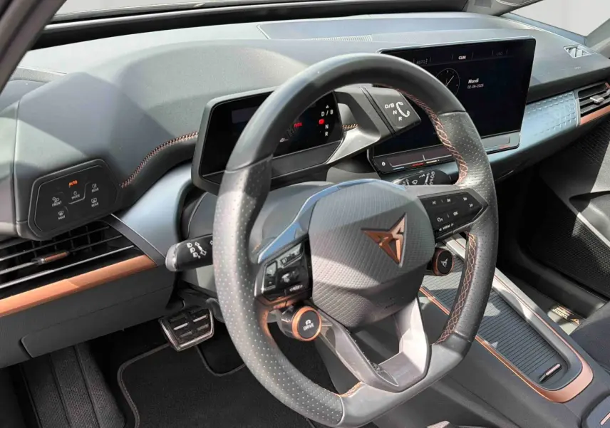 Vue intérieure centrée sur le volant multifonction noir avec surpiqûres cuivre du CUPRA Born 2024.