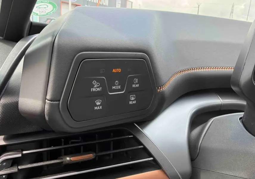 Détail du tableau de bord côté gauche du CUPRA Born blanc 2024 avec commandes d’éclairage et surpiqûres orange.