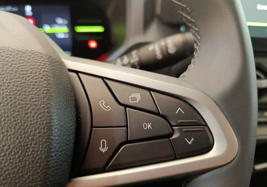 Gros plan sur les commandes multifonctions à droite du volant cuir du Dacia Duster Journey Hybrid 155 noir 2026.