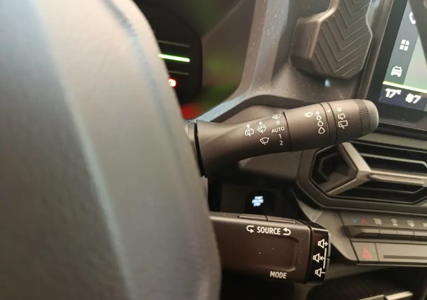 Gros plan sur les commandes au volant et la manette d’essuie-glace du tableau de bord du Dacia Duster noir hybride 2026.