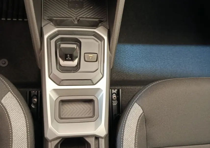 Vue plongeante sur la console centrale du Dacia Duster noir 2026, avec levier de vitesse automatique et sièges tissu gris.