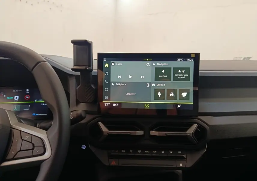 Vue intérieure centrée sur l’écran tactile et le tableau de bord du Dacia Duster Journey Hybrid 155 noir, avec volant partiel visible.