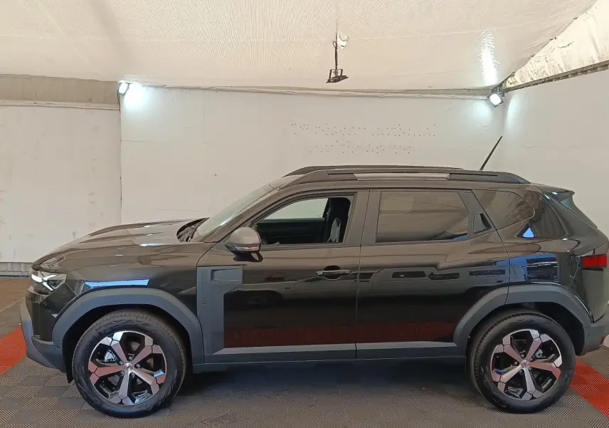 Vue de profil côté gauche du Dacia Duster Journey Hybrid 155 noir, avec jantes alliage et barres de toit noires.