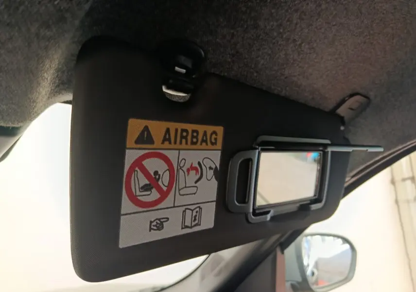 Détail intérieur du pare-soleil côté conducteur du Dacia Duster noir 2026, avec miroir et avertissement airbag visible.