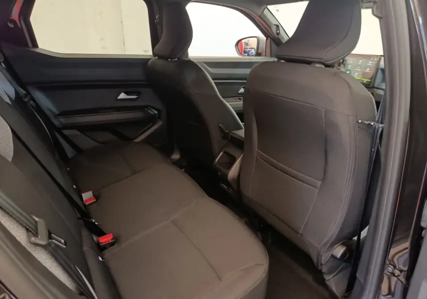 Vue intérieure côté arrière droit du Dacia Duster Journey Hybrid 155 noir, montrant les sièges arrière et la console centrale.