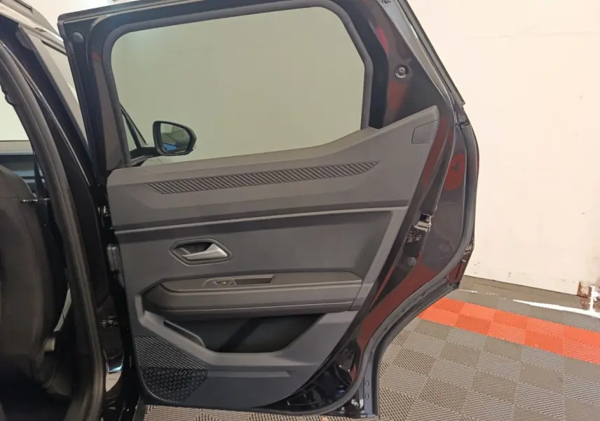 Vue intérieure de la porte arrière droite noire du Dacia Duster Journey Hybrid 155 avec détails des commandes et rangement.