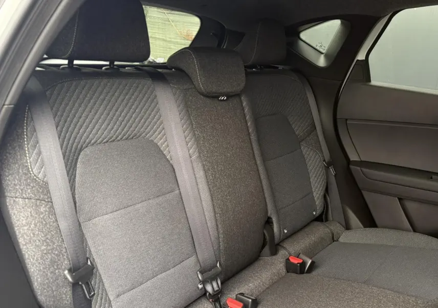 Vue intérieure côté droit des sièges arrière en tissu gris du Renault Captur blanc nacré 2026 avec ceintures de sécurité visibles.