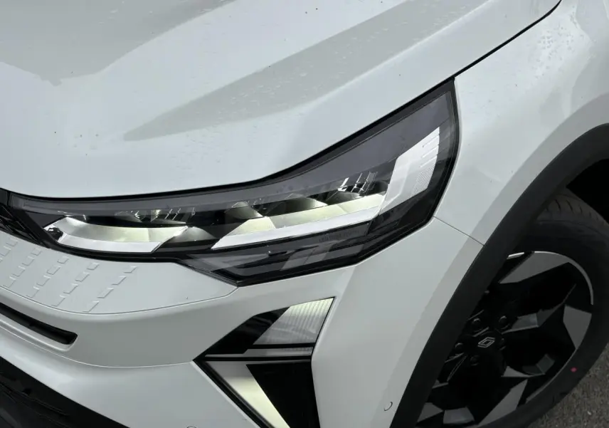 Gros plan sur l'avant droit du Renault Captur blanc nacré, mettant en valeur le phare LED et la jante noire.