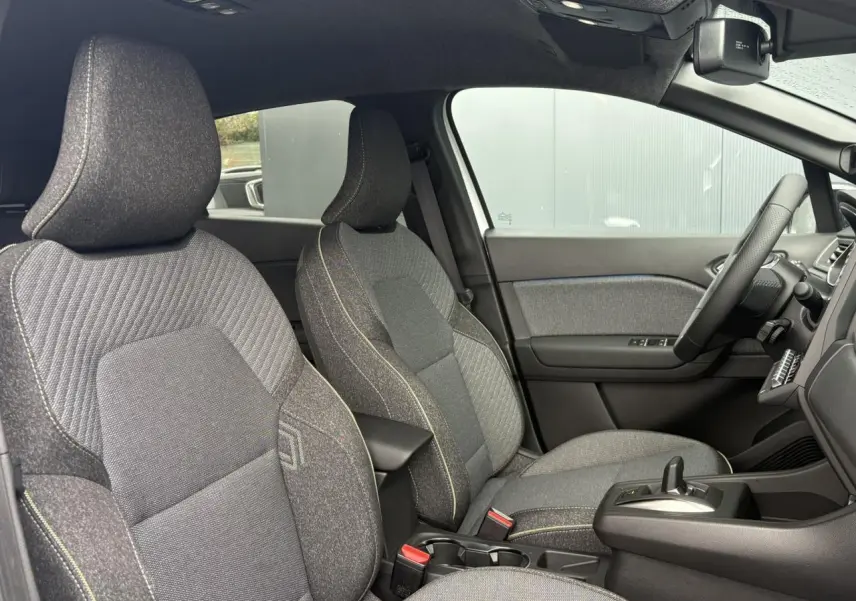 Vue intérieure côté droit du Renault Captur 2026, sièges tissu gris avec console centrale et volant textile.