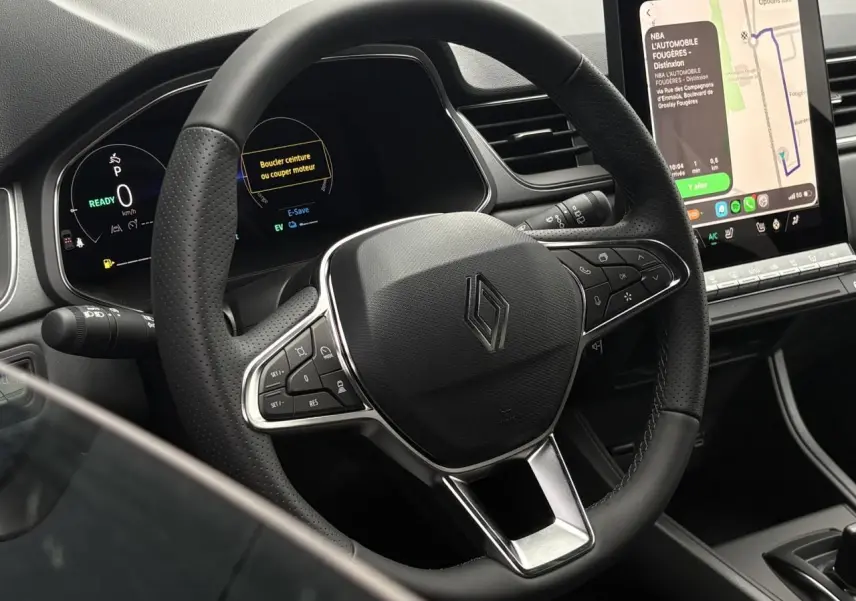 Vue rapprochée du volant noir perforé et du tableau de bord numérique du Renault Captur 2026 avec écran tactile central.