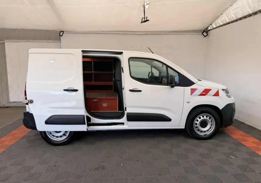 Vue latérale droite d’un Citroën Berlingo blanc 2019 avec porte coulissante ouverte et marquages rouges sur l’aile avant.