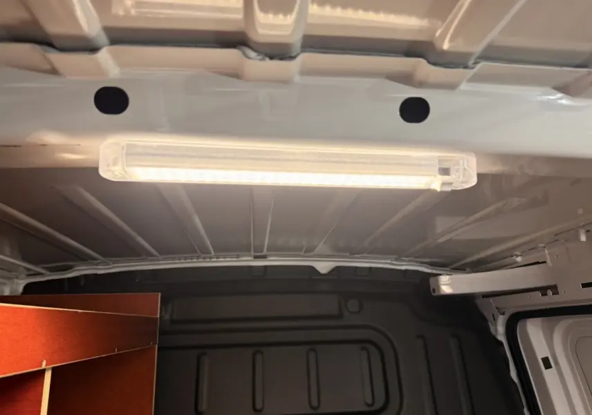 Intérieur du coffre d’un Citroën Berlingo blanc 2019, vue du plafond avec éclairage LED et aménagement bois latéral.