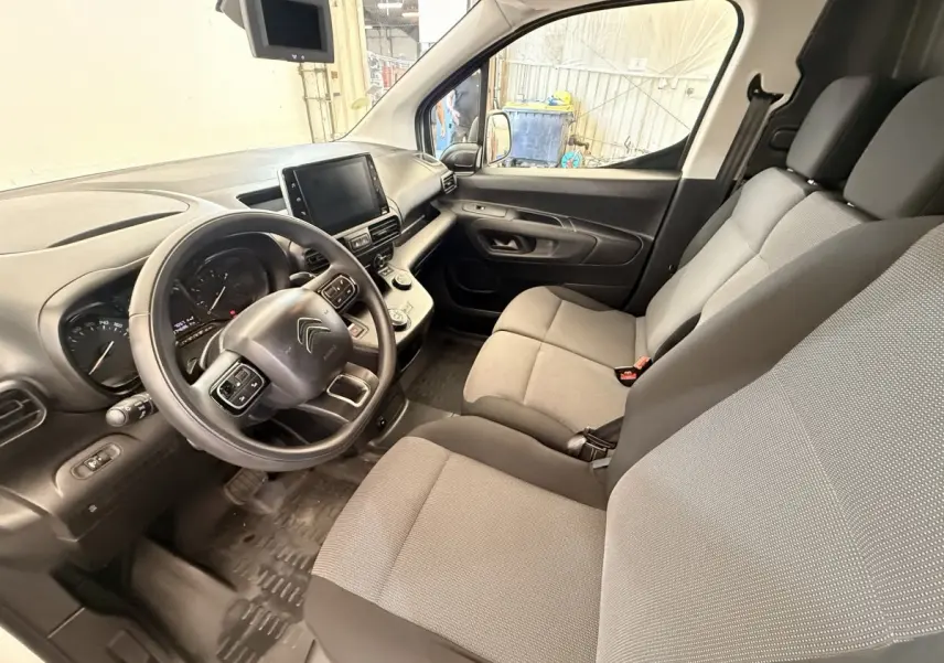 Vue intérieure côté conducteur du Citroën Berlingo 2019 avec tableau de bord noir et sièges tissu gris.