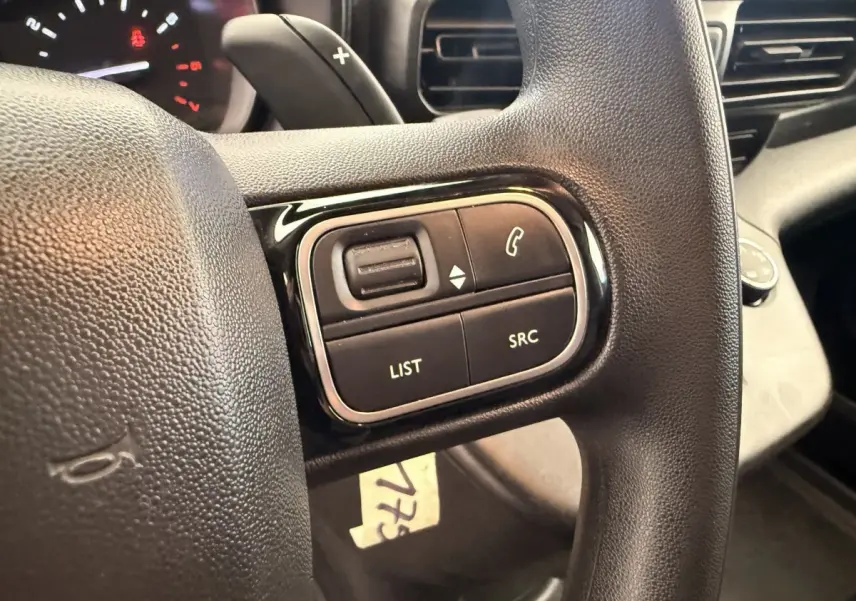 Gros plan sur les commandes multifonctions noires du volant du Citroën Berlingo 2019, intérieur noir.