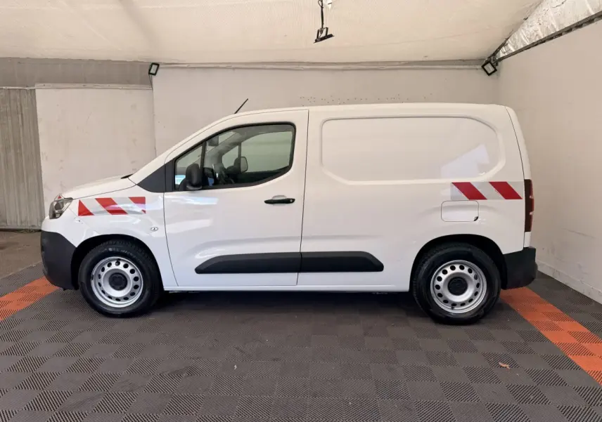 Vue de profil côté gauche d’un Citroën Berlingo blanc 2019 avec bandes réfléchissantes rouges sur les ailes avant et arrière.