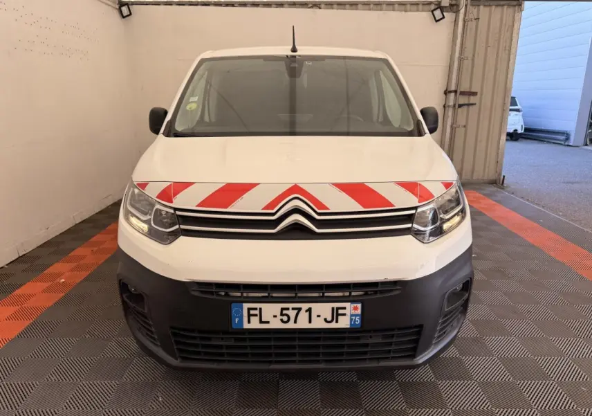 Vue de face d'un Citroën Berlingo blanc 2019 avec bande rouge et blanche sur le capot, dans un garage.
