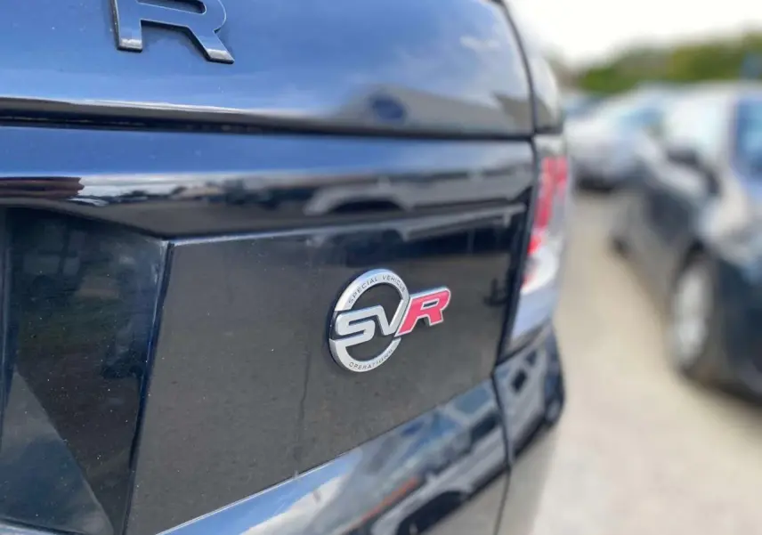 Gros plan sur l'arrière noir brillant d'un Range Rover Sport SVR avec le badge SVR rouge et argent visible.